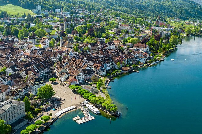 Veloweg-Initiative Zug Ablehnung. Luftaufnahme einer Stadt am See. 