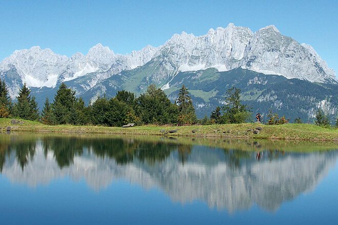 Das Kaisergebirge: Als Reflexion im Schlosserbergsee noch einen Tick schöner, als es sowieso schon ist. Kaisergebirge in Kitzbühl mit dem Mountainbike. Ein Berg reflektiert in einem Bergsee.