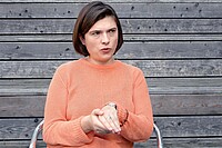 Die Geschichte des Radfahrens in der Ukraine. Eine Frau in einem oragen Pullover sitzt auf einem Stuhl.