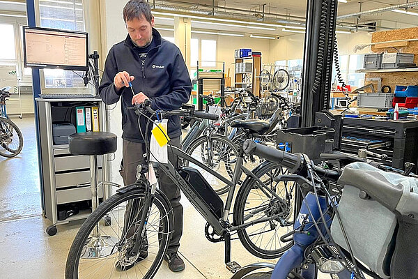 Ein Mann arbeitet in einer Werkstatt an einem Fahrrad.