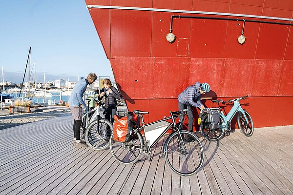 Drei Radfahrer packen Taschen auf Velos.