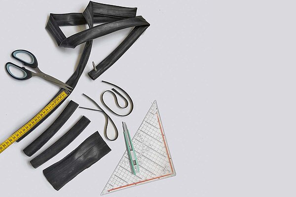 Tool-Kit aus alten Fahrradschläuchen. Schere, Geodreieck und alte Fahrradschläuche liegen auf einem Tisch.
