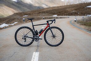 Ein Rennrad steht in der Mitte einer Strasse. Im Hintergrund Berge.