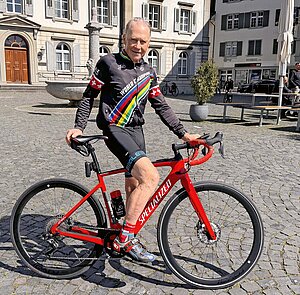 Ein älterer Mann mit einem roten Rennrad.