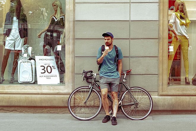 Veloverkäufe in Österreich boomen. Ein Mann steht an sein Rad angelehnt und isst ein Eis.