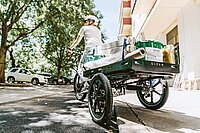 Dreirädriges Lastenvelo fährt über einen Bordstein.