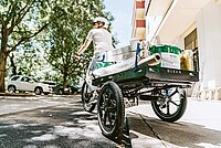 Dreirädriges Lastenvelo fährt über einen Bordstein.