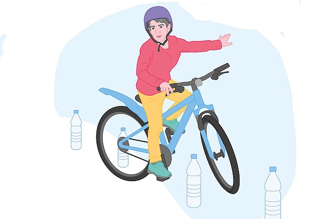 Ein Kind mit rotem Pullover und gelber Hose fährt auf einem Fahrrad.