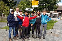 Schule Velo Integration. Eine Gruppe Männer steht in Wanderbekleidung vor einem Wegweise. 