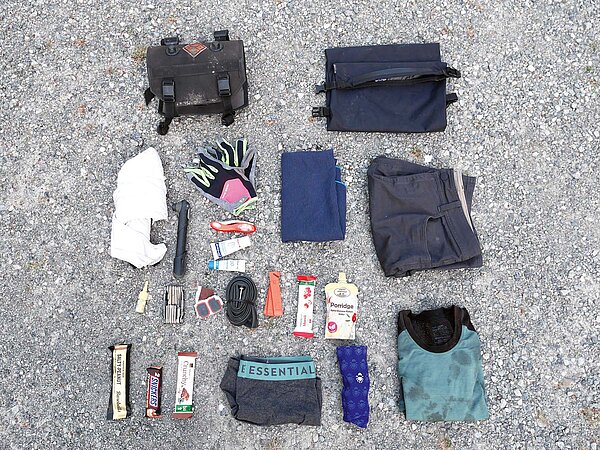 Auslegeordnung von Material für Fahrradtour am Boden. 