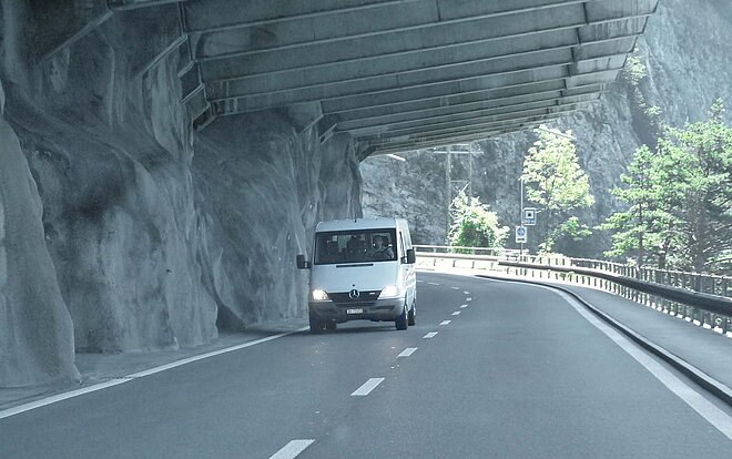 weisser Lieferwagen fährt unter Felsüberhang auf der Axenstrasse 