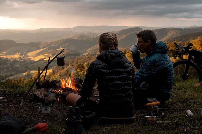 Supernova Nachhaltigkeitsbericht. Zwei Personen sitzen auf der Wiese und betrachten den Sonnenuntergang..