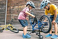 Praktisches Velozubehör für Kinder. Zwei Mädchen stehen neben einem Velo. 