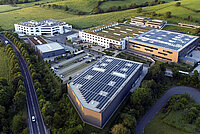 Luftaufnahme von Gebäuden mit Photovoltaik-Anlagen auf den Dächern.