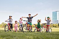 Kinder mit Fahrrädern auf grüner Wiese.