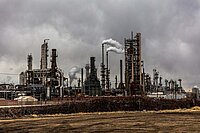 Eine düstere Industrieanlage mit vielen rauchenden Schornsteinen.