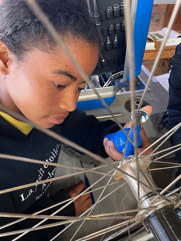 Eine junge Frau arbeitet an einen Laufrad eines Fahrrads.
