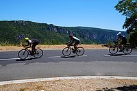 Radfahrer fahren hintereinander eine Strasse hinunter. 