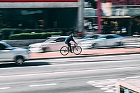 Ein Radfahrer fährt auf einem rot markierten Radweg in einer Stadt.