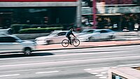 Ein Radfahrer fährt auf einem rot markierten Radweg in einer Stadt.