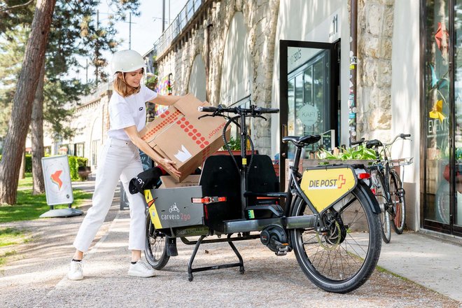 Das Cargobike-Sharing von Carvelo2go ist ein Erfolg. Eine junge Frau lädt Pakete auf ihr E-Cargobike.