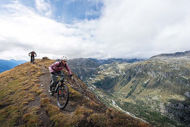 St. Gotthard Pässe Bike Tour. Eine Mountainbikerin fährt auf einem Singletrail in den Schweizer Alpen.