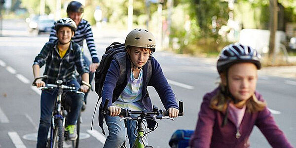 Kinder fahren auf ihren Velos. Alle tragen einen Helm.