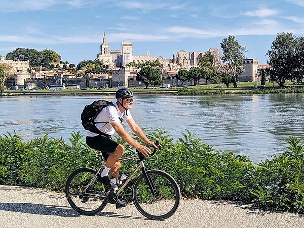 Ein Mann fährt auf dem Gravelbike an einem Flussufer.