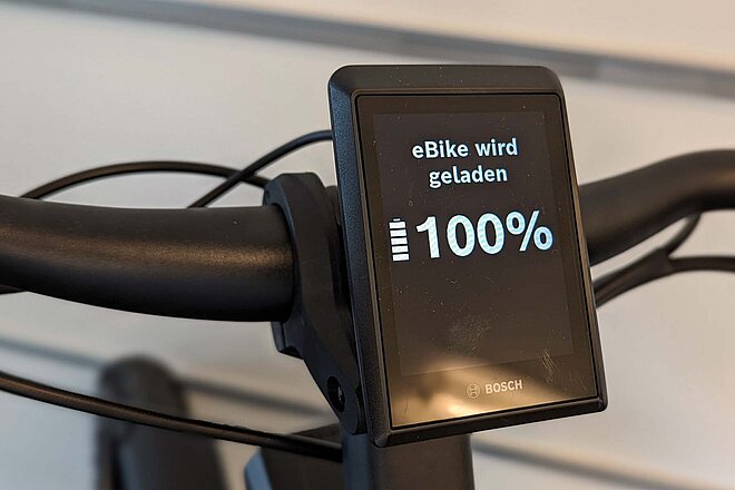 Wie teuer ist eine Akkuladung? Mit unserem Beispiel können Sie die Kosten selbst berechnen. Was kostet das Aufladen des E-Bike Akkus. Ein Display zeigt an, dass ein Akku voll geladen ist.