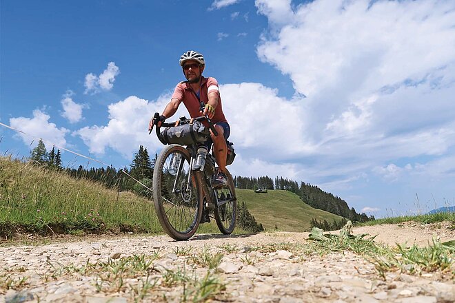 Ein Mann fährt mit einem Gravelbike auf einem Schotterweg.
