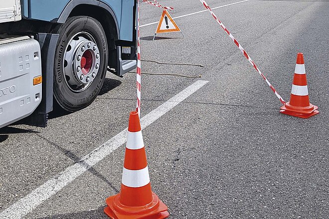 Absperrbänder und Pylonen zeigen auf, was vom Lastwagen aus alles nicht sichtbar ist. Mit dem LKW den toten Winkel erleben. Verkehrspylonen stehen auf der Strasse.