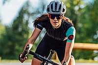 Frau auf dem Rennrad mit blauem Helm und schwarzen Tricot