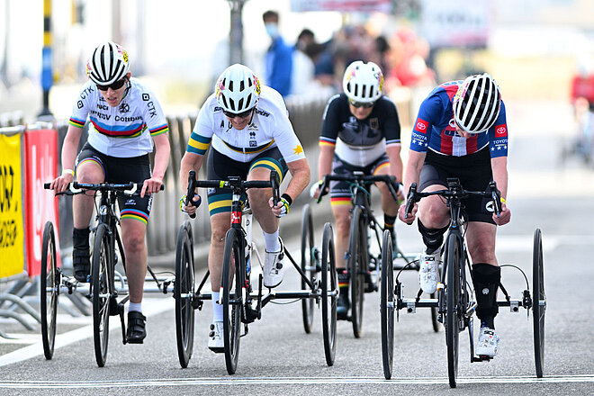 4 Velofahrer nehmen mit einem Dreirad an einem Velorennen teil.