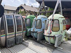 In Cluses sterben die alten Gondeln vor sich hin. Alte Liftgondeln stehen auf einem Platz.