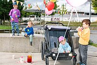 Kinder sitzen in einem Kindernahänger für Fahrräder.