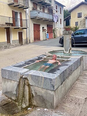 Ein Mann liegt mit Badehose in einem Brunnen.