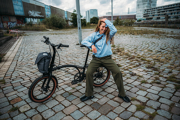 Eine junge Frau sitzt auf einem Faltrad von Brompton.