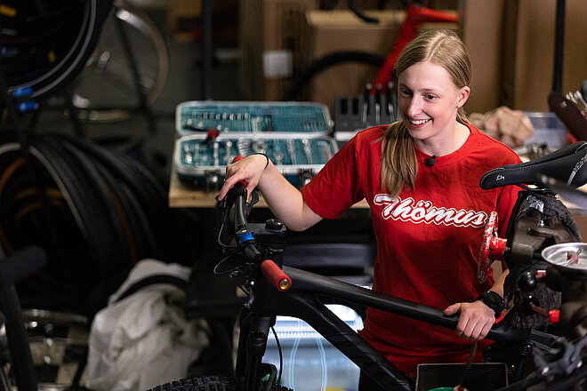 Eine junge Frau steht hinter einem Fahrrad.
