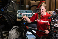 Eine junge Frau steht hinter einem Fahrrad.