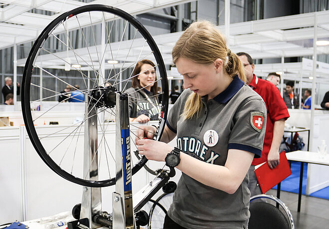 Eine junge Frau arbeitet an einem Zentrierständer für Fahrradräder
