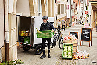 Ein Mann lädt Kisten aus einem Lastenfahrrad aus