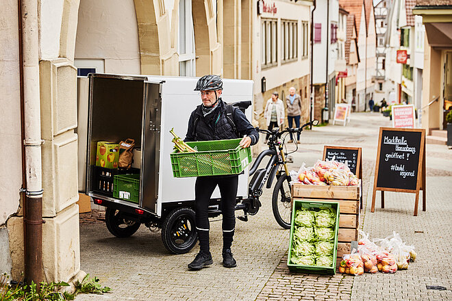 Ein Mann lädt Kisten aus einem Lastenfahrrad aus