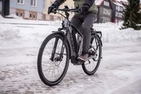 Eine Person fährt mit dem E-Bike auf einer verschneiten Strasse