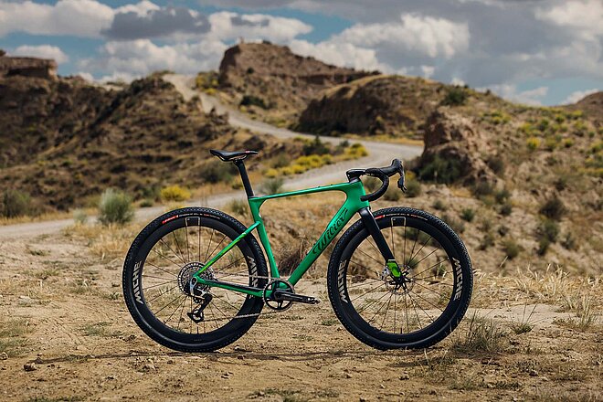 Ein Gravelbike steht in einer kargen Wüstenlandschaft.