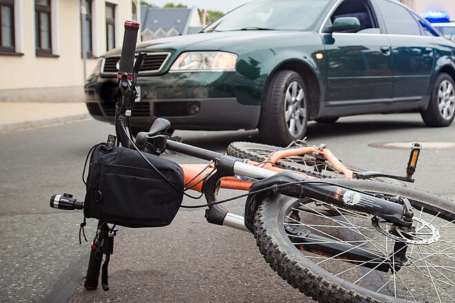 Ein Fahrrad liegt vor einem Auto auf der Strasse