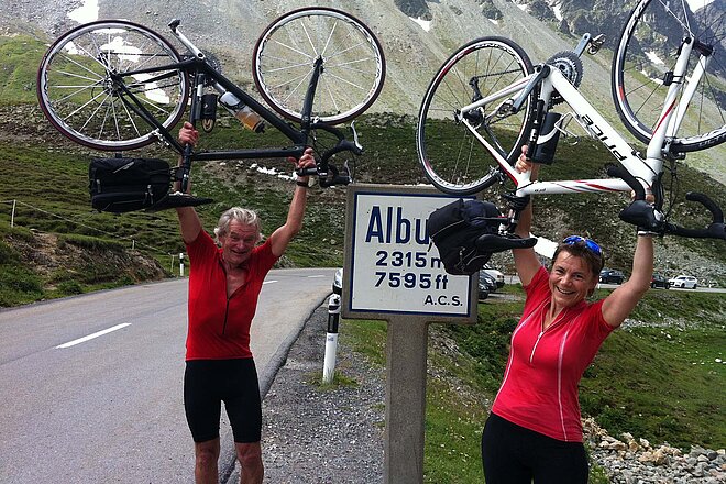 Ein Mann und eine Frau halten ihre Rennvelos in die Luft