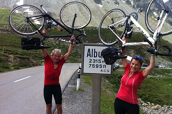 Ein Mann und eine Frau halten ihre Rennvelos in die Luft