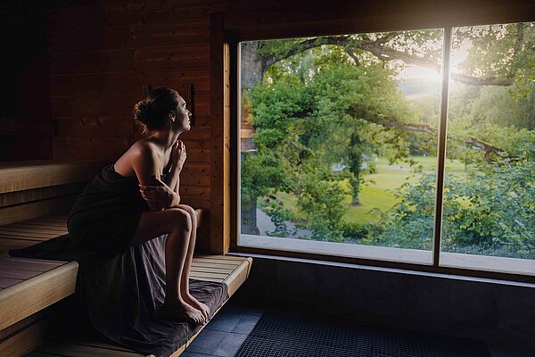 Wellness-Wonnen Aargauer Thermalbäder. Eine Frau mit Handtuch sitzt in der Sauna.