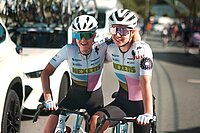 Zwei junge Frauen mit Fahrradtricots, Rennradhosen, Helm, Sonnenrbille und Rennrad.