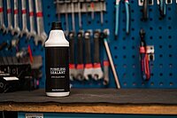 Eine Flasche mit weissem Inhalt steht auf einer Werkbank.